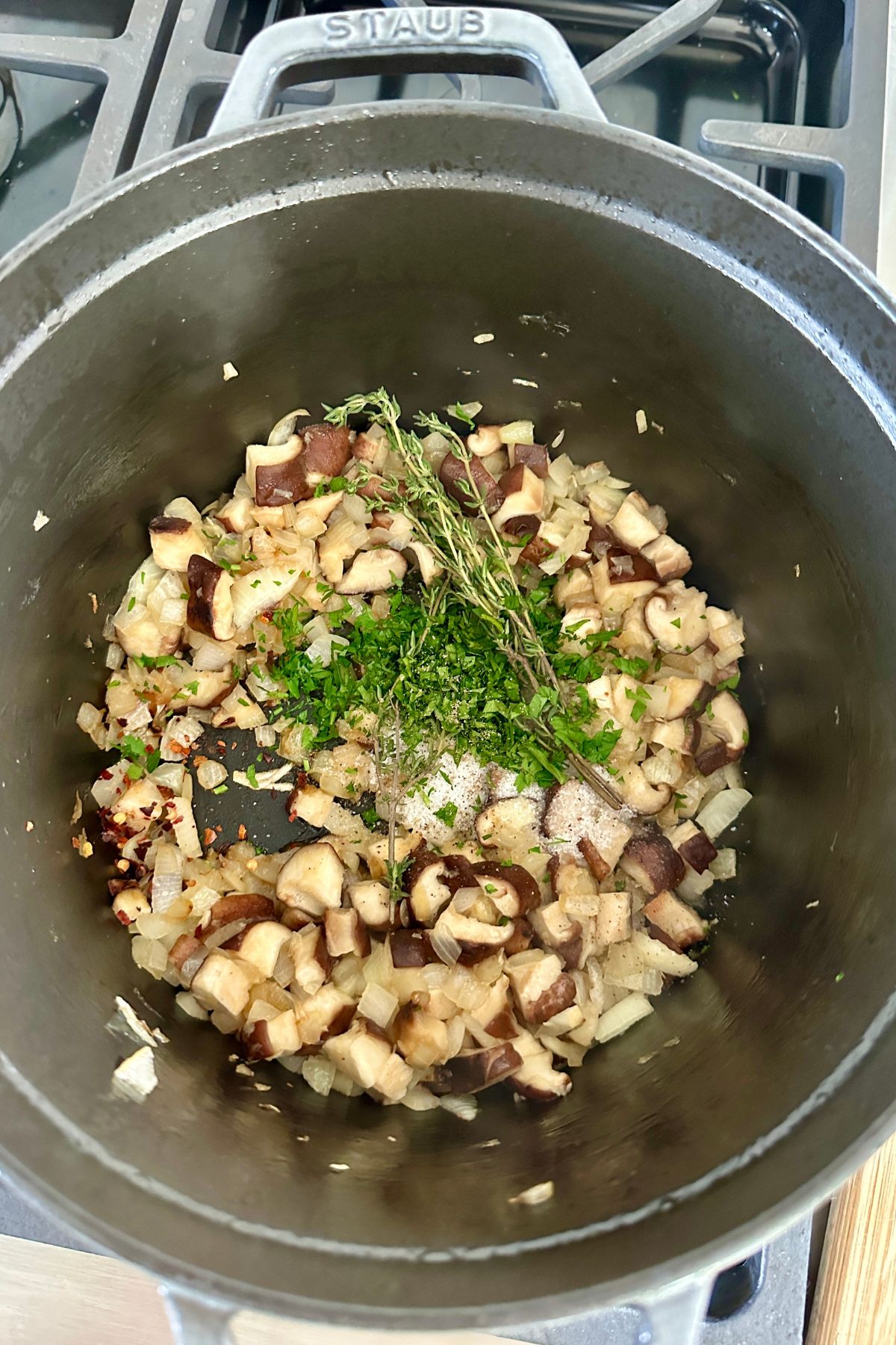 vegetable pieces in a soup pot with fresh herbs on top